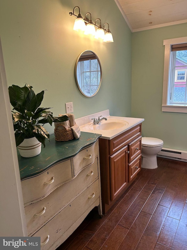 bathroom featuring toilet, baseboard heating, vanity, ornamental molding, and hardwood / wood-style flooring