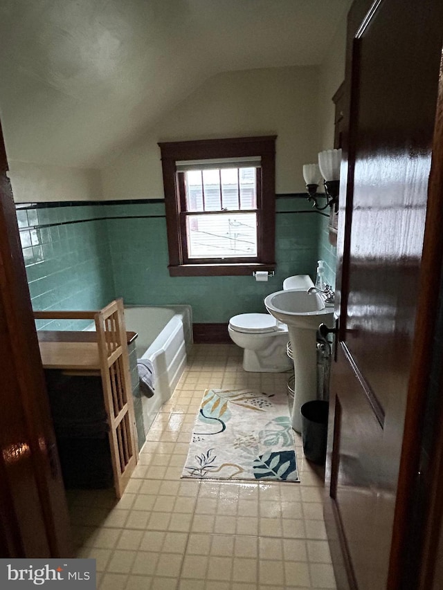 full bath featuring a bath, toilet, vaulted ceiling, and tile walls