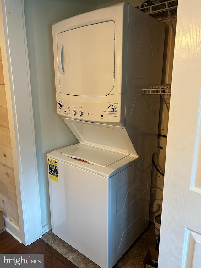laundry room with laundry area, stacked washer / drying machine, and dark wood-style floors