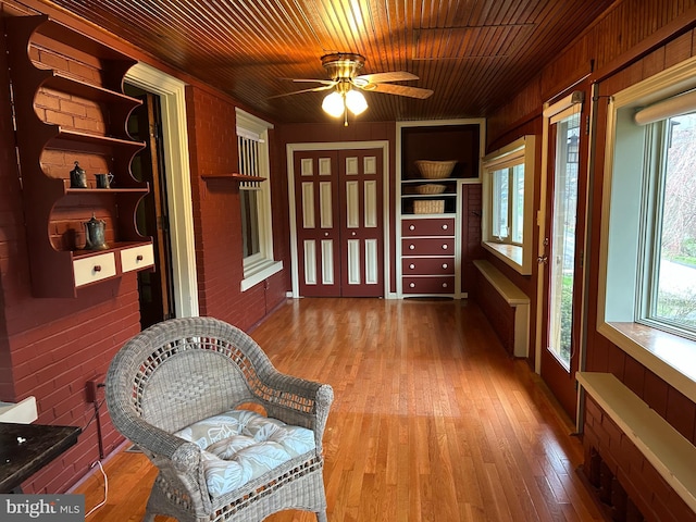 interior space featuring wood finished floors, built in shelves, wooden ceiling, ceiling fan, and wooden walls