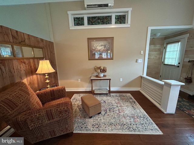 sitting room with baseboards, dark wood finished floors, and a wall mounted AC