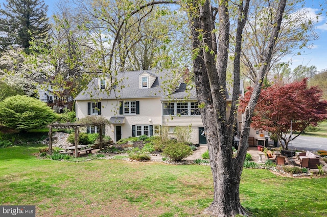 view of front of property with a pergola, stucco siding, a patio area, and a front lawn