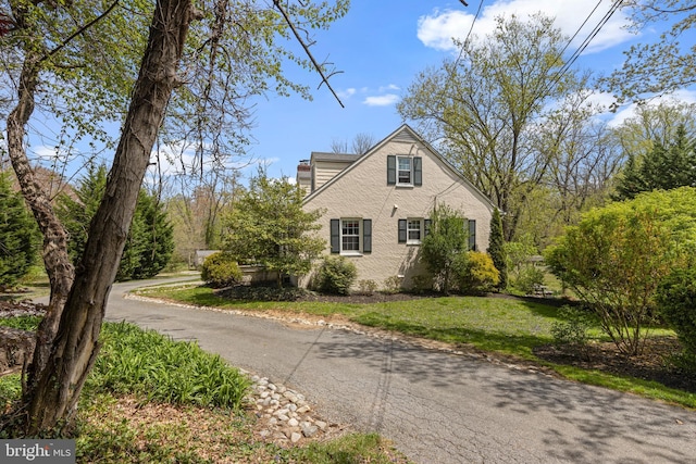 view of home's exterior featuring a chimney and a lawn