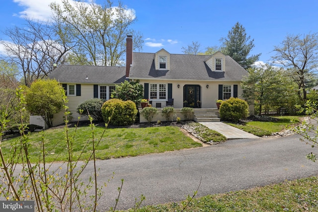 cape cod-style house with a front lawn and a chimney