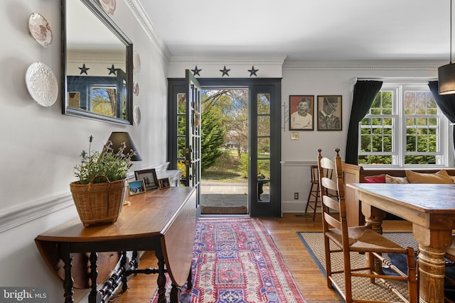 doorway to outside with crown molding and wood finished floors