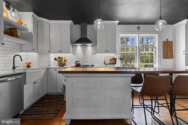 kitchen with a center island, wood finished floors, wall chimney exhaust hood, dishwasher, and butcher block counters