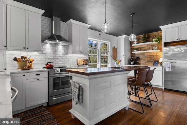 kitchen featuring wall chimney exhaust hood, stainless steel appliances, dark wood-type flooring, and backsplash