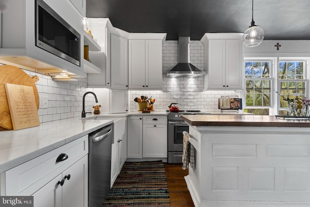 kitchen with wall chimney exhaust hood, backsplash, dark wood-style floors, white cabinets, and appliances with stainless steel finishes