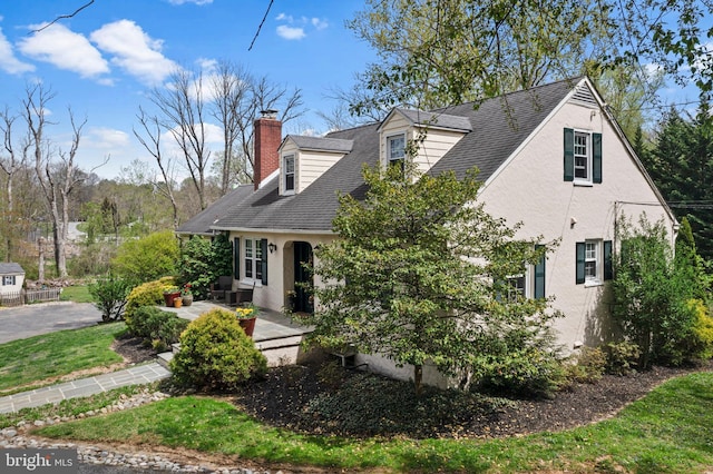 view of front of house with a shingled roof, stucco siding, and a chimney