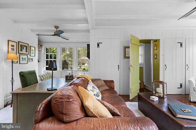 living area featuring a ceiling fan, beamed ceiling, and wood finished floors