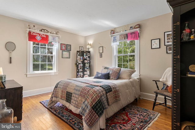 bedroom featuring multiple windows, baseboards, and hardwood / wood-style floors