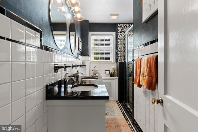bathroom featuring tile walls, tile patterned flooring, a stall shower, and a sink