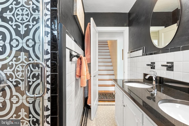 full bathroom featuring tile patterned floors, tile walls, double vanity, and a sink