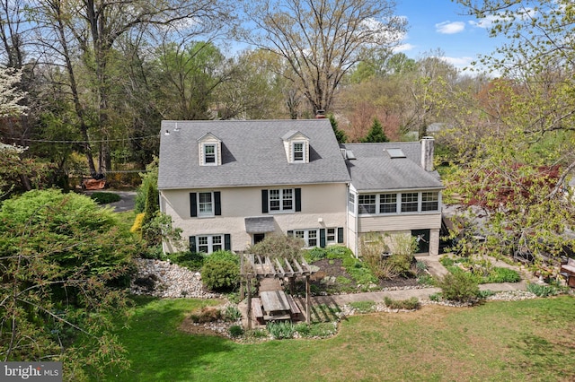 back of property featuring roof with shingles, a sunroom, a chimney, and a lawn