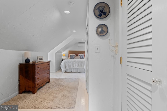 bedroom with vaulted ceiling, wood finished floors, a wall mounted AC, and recessed lighting