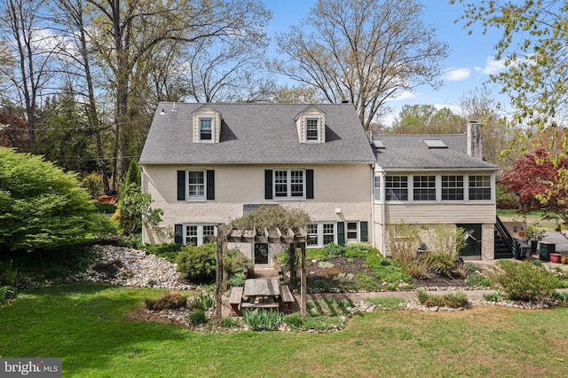 back of property featuring a sunroom, stucco siding, a chimney, a lawn, and stairway