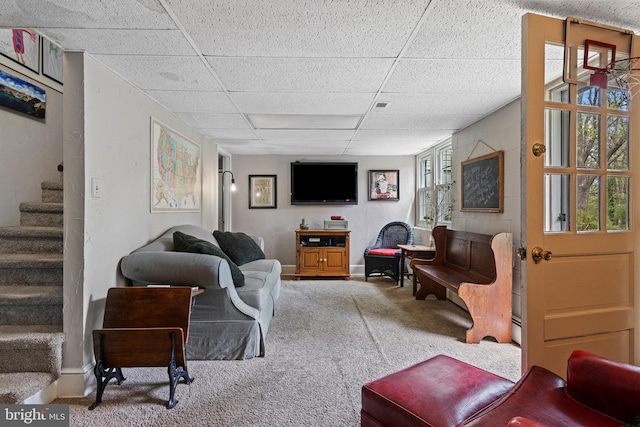 living area with a paneled ceiling, stairs, carpet flooring, and baseboards