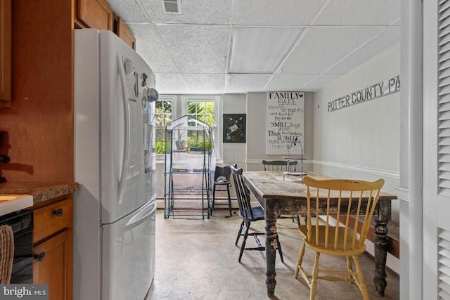 dining space featuring a paneled ceiling, finished concrete flooring, and visible vents