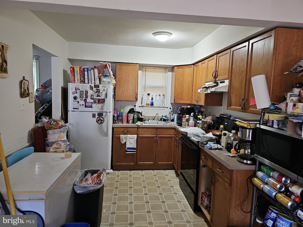 135 Hampshire Rd, Sicklerville, NJ 08081 - kitchen with freestanding refrigerator, black electric range, brown cabinetry, a sink, and stainless steel microwave