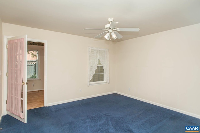 empty room with baseboards, a ceiling fan, and dark carpet