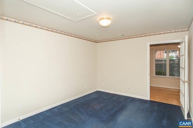spare room featuring baseboards and dark colored carpet