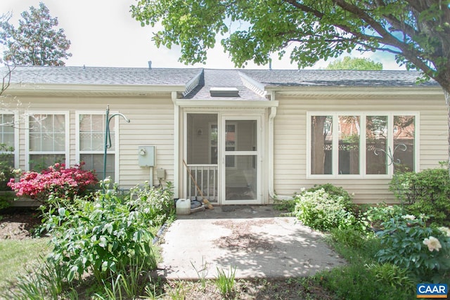 rear view of house with a shingled roof and a patio area