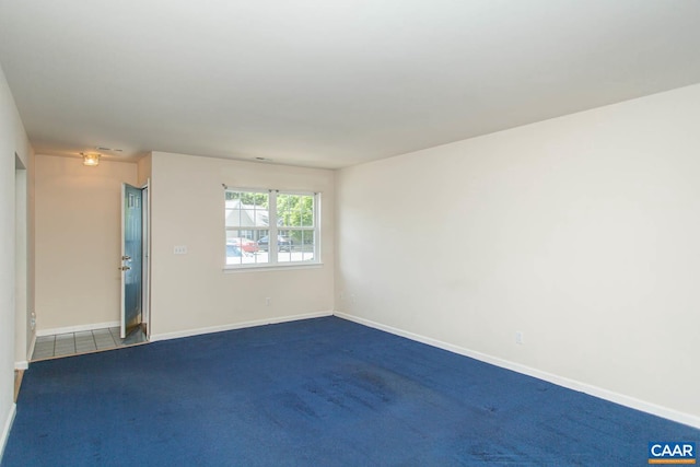 unfurnished room with baseboards and dark colored carpet