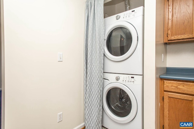 laundry room featuring laundry area, stacked washer and clothes dryer, and baseboards