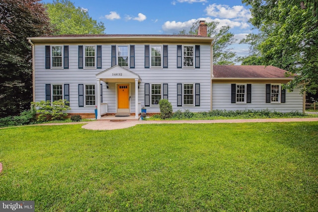 colonial house featuring a front lawn and a chimney