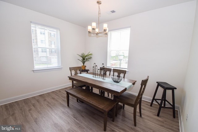 dining area with a chandelier, wood finished floors, and baseboards