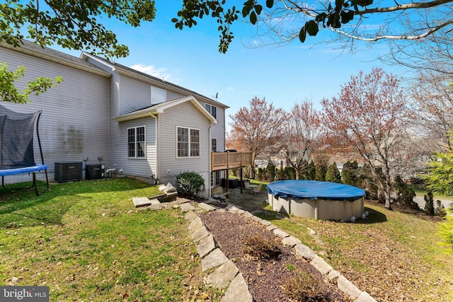 3 Oleander Dr, Stafford, VA 22554 - view of yard featuring central air condition unit, a trampoline, a wooden deck, and a covered pool