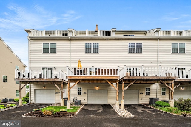 back of property featuring central AC, an attached garage, asphalt driveway, and a deck