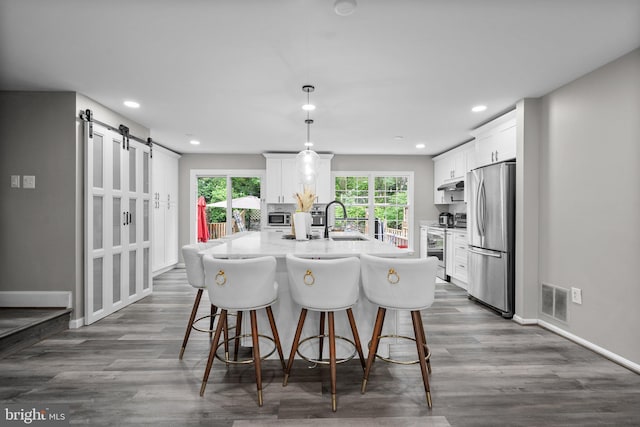 1949 Catoctin Ter, Silver Spring, MD 20906 - kitchen with stainless steel appliances, a barn door, under cabinet range hood, white cabinets, and recessed lighting