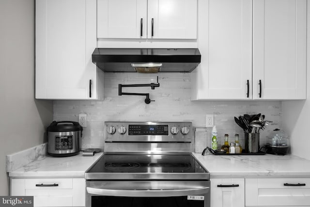 1949 Catoctin Ter, Silver Spring, MD 20906 - kitchen featuring stainless steel range with electric stovetop, extractor fan, white cabinetry, tasteful backsplash, and light stone counters