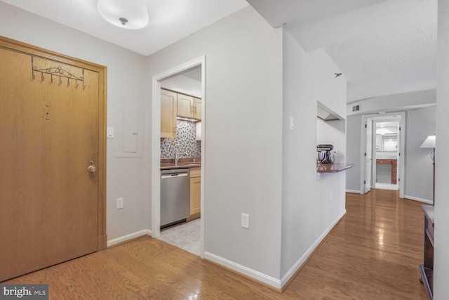 foyer with light wood finished floors, a textured ceiling, and baseboards