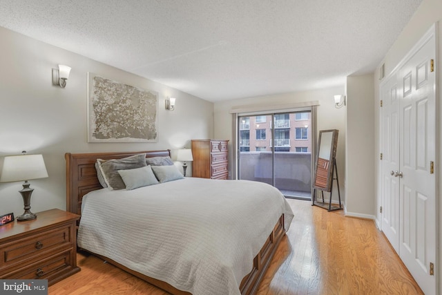 bedroom featuring light wood-style floors, access to exterior, a textured ceiling, and a closet