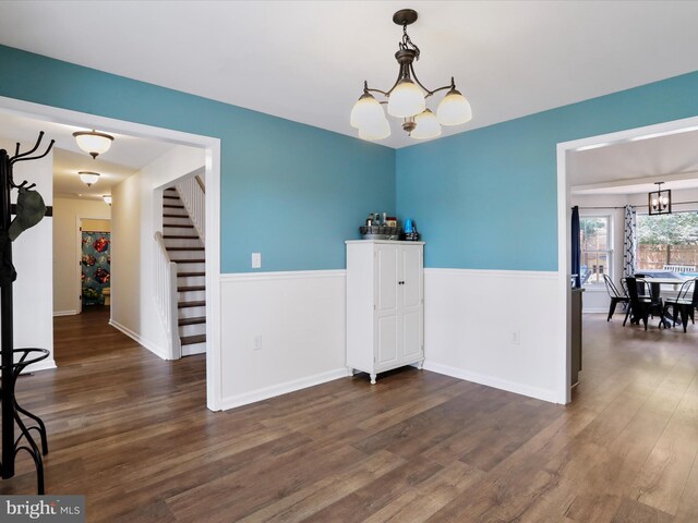 dining space featuring a chandelier, stairs, wood finished floors, and baseboards