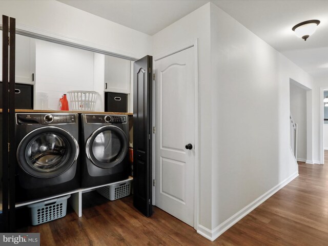 washroom with wood finished floors, washer and dryer, and baseboards