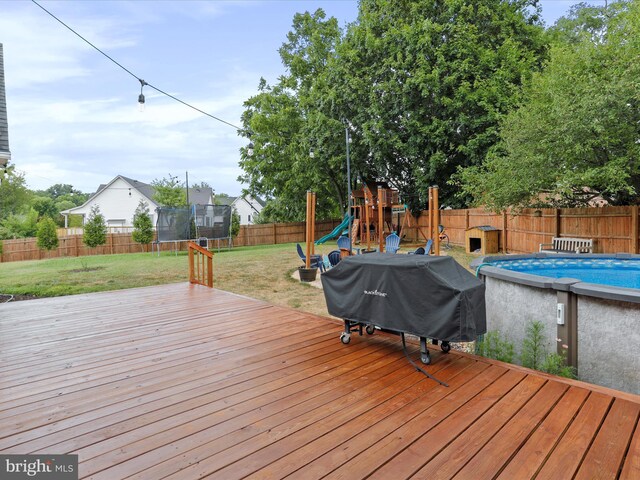 deck featuring a trampoline, a playground, and a grill