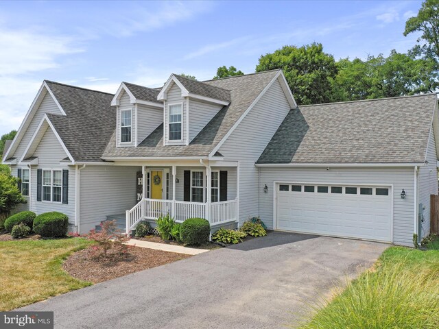 cape cod-style house featuring a porch, asphalt driveway, an attached garage, and a shingled roof