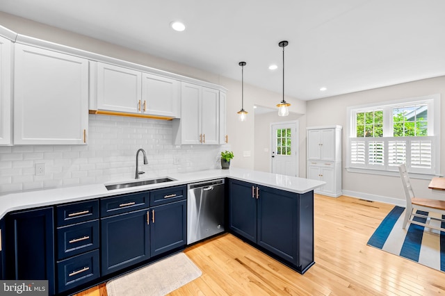 kitchen with stainless steel dishwasher, blue cabinets, a sink, light wood-style floors, and recessed lighting