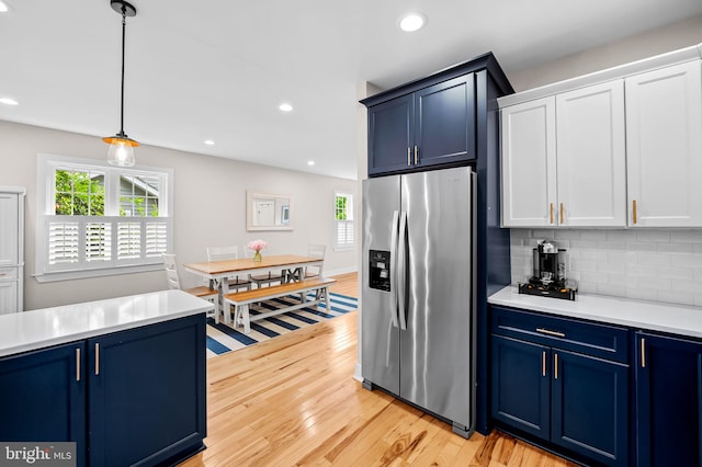 kitchen featuring stainless steel refrigerator with ice dispenser, blue cabinetry, plenty of natural light, and recessed lighting