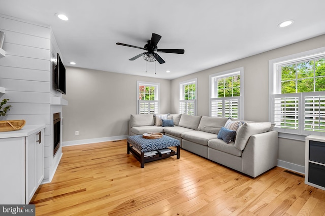 living room with recessed lighting, ceiling fan, light wood finished floors, baseboards, and a fireplace