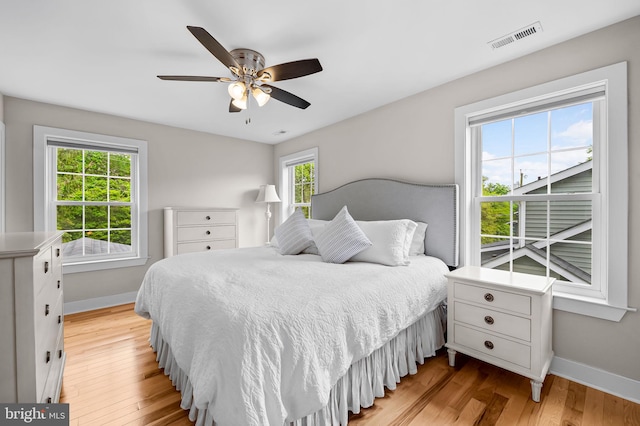 bedroom featuring multiple windows, baseboards, and light wood-type flooring