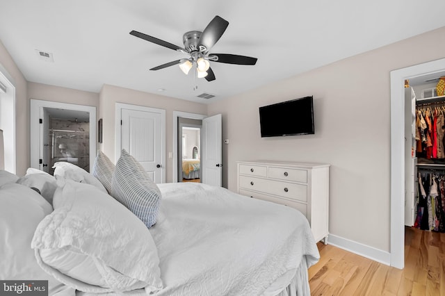 bedroom featuring a closet, a spacious closet, light wood-style floors, baseboards, and ceiling fan