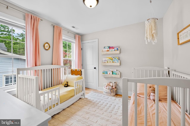 bedroom featuring wood finished floors, a closet, a crib, and baseboards