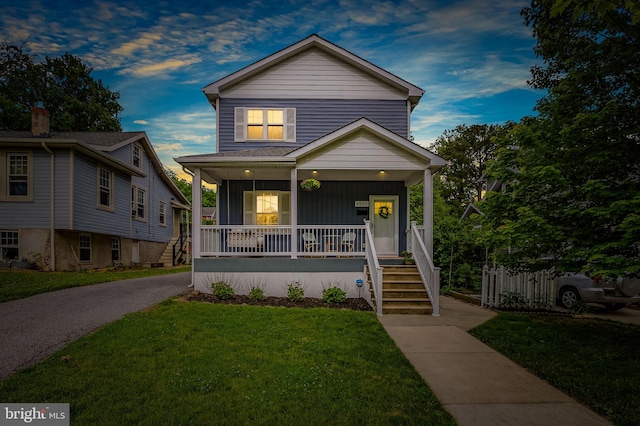 view of front of house with covered porch, a front lawn, and board and batten siding