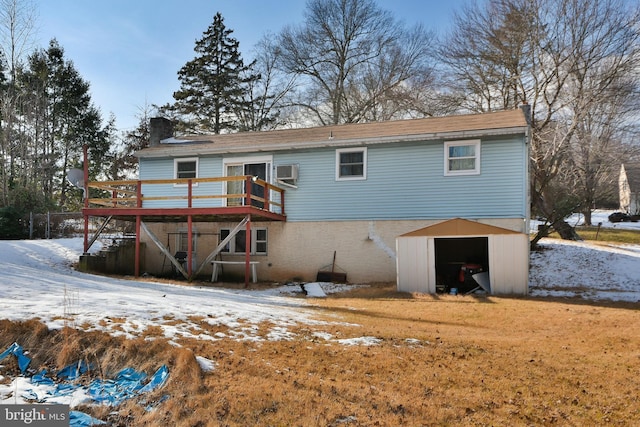 snow covered property with a chimney, a wooden deck, a shed, an outbuilding, and an AC wall unit