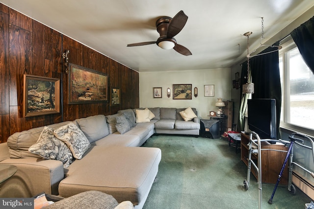 carpeted living area with a ceiling fan and wood walls