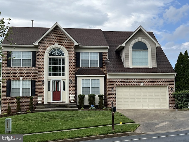 colonial house with concrete driveway, a garage, brick siding, and a front yard